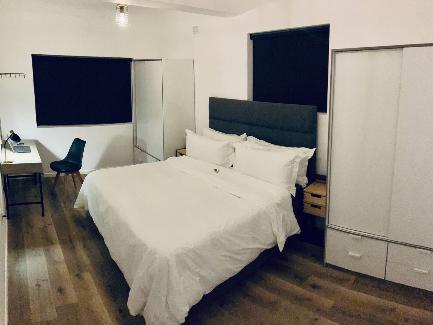 King bedroom with white linen, work desk and wardrobes